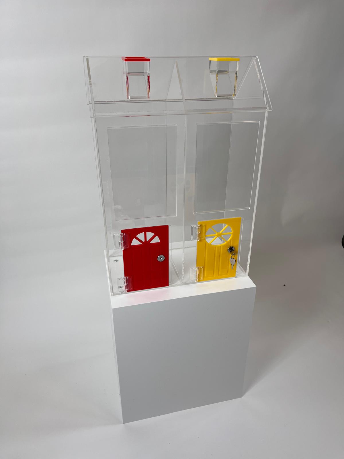 Two-house acrylic reward token unit shaped like a school building with red and yellow lockable doors, mounted on a white plinth